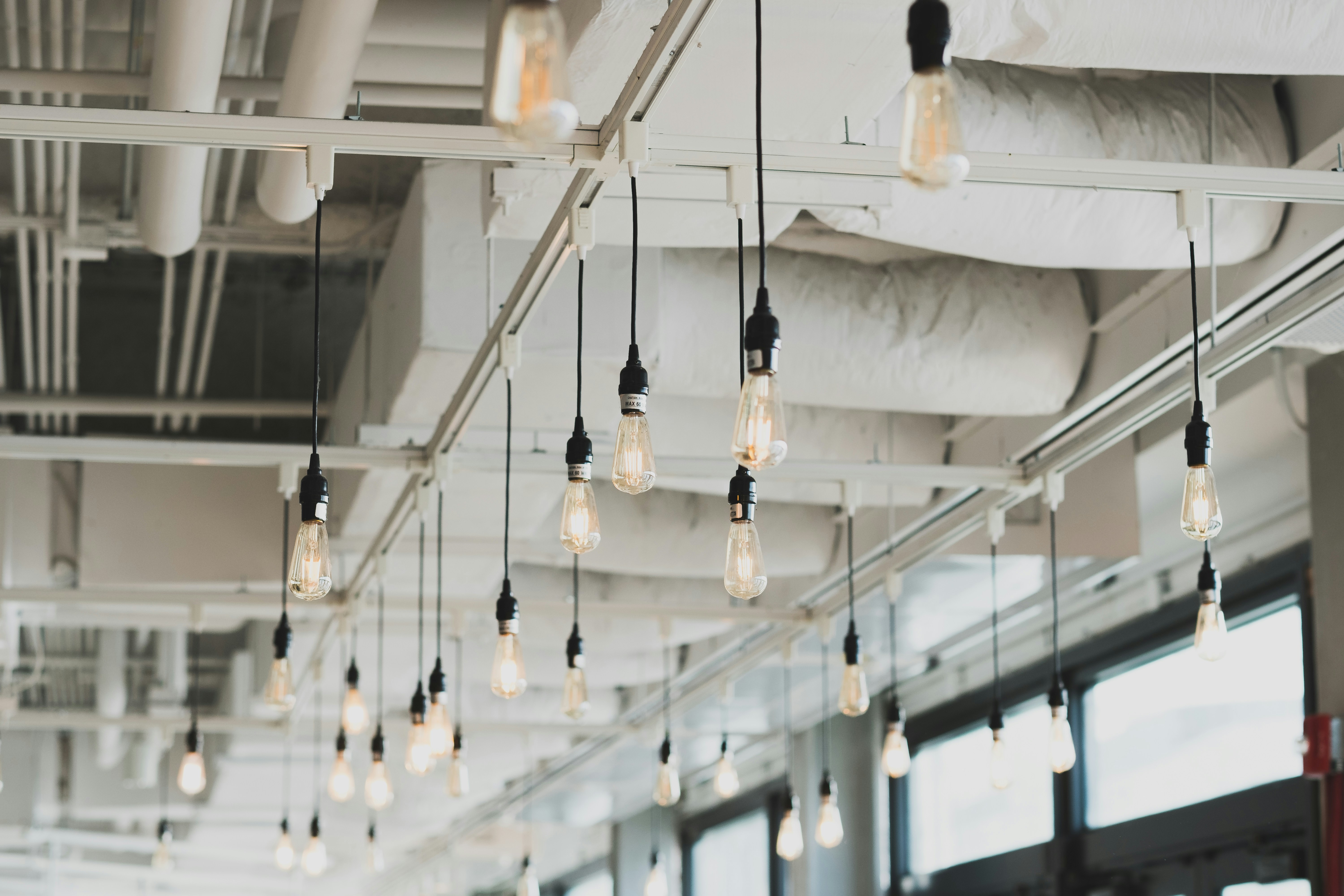 Pendant LED bulbs hanging from exposed ceiling tracks in a commercial interior
