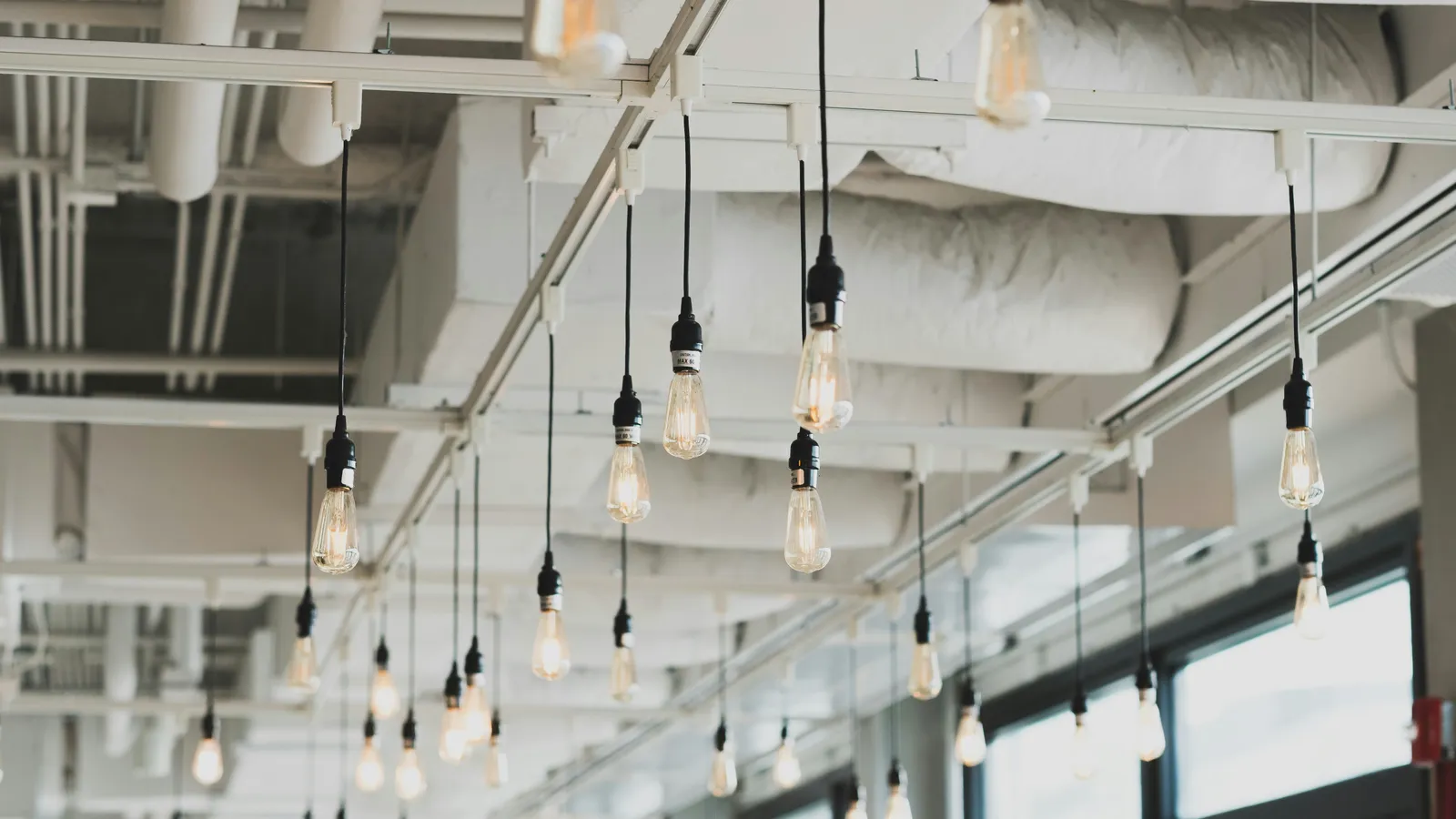 Pendant LED bulbs hanging from exposed ceiling tracks in a commercial interior